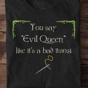 Op de afbeelding: Zwart T-shirt met een witte afbeelding met de tekst "You say "Evil Queen" like it's a bad thing" met een illustratie van een groene naald en een gele draad.