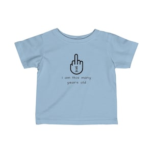 K&ouml;nnte beinhalten: Hellblaues Baby-T-Shirt mit einer schwarzen Grafik eines Mittelfingers mit der Zahl 1 im Finger. Der Text unter der Grafik lautet "Ich bin so viele Jahre alt".