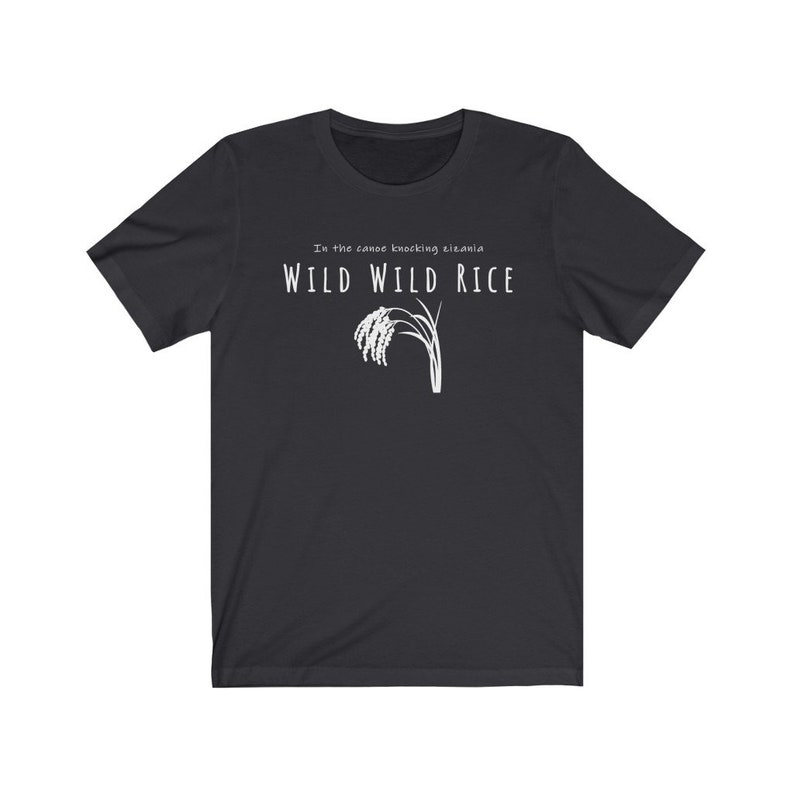Puede incluir: Una camiseta negra con texto blanco que dice "In the canoe knocking elania WILD WILD RICE" y un gr&aacute;fico de un tallo de arroz.