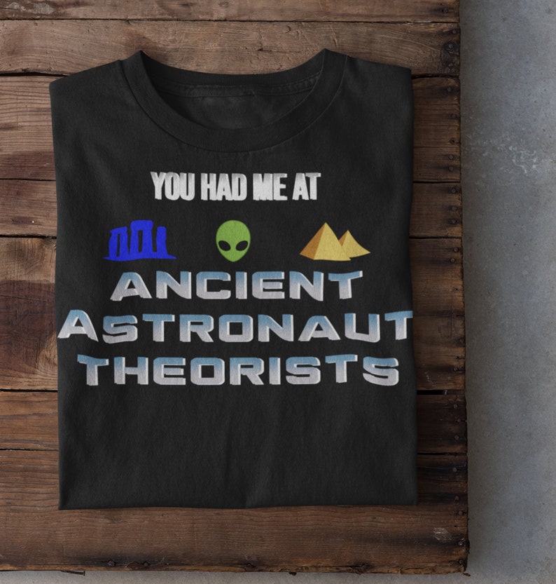 May include: Black t-shirt with the text "You had me at Ancient Astronaut Theorists" in white with blue and yellow icons of a pyramid, an alien, and a building.