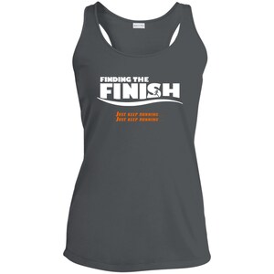 Op de afbeelding: Een donkergrijs tanktop met de tekst "FINDING THE FINISH" in wit met een hardlopende figuur in oranje. De tekst "JUST KEEP RUNNING" wordt twee keer in oranje onder de hoofdtekst herhaald.
