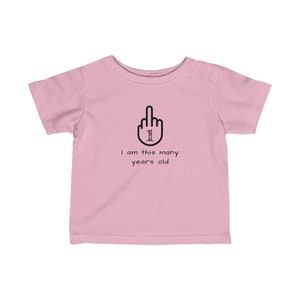 K&ouml;nnte beinhalten: Rosafarbenes Baby-T-Shirt mit einem schwarzen Mittelfinger, auf dem die Zahl 1 steht. Der Text darunter lautet "Ich bin so alt".