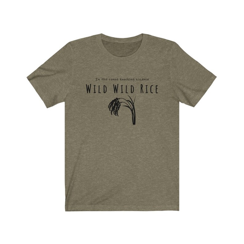 Puede incluir: Una camiseta verde con el texto "In the canoe knocking, sis, and WILD WILD RICE" y una silueta negra de un tallo de arroz.