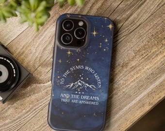 Könnte beinhalten: Dunkelblaue Handyhülle mit Sternennacht-Design und goldenen Akzenten. Die Hülle zeigt den Text "TO THE STARS WHO LISTEN AND THE DREAMS THAT ARE ANSWERED" mit einer Bergillustration.