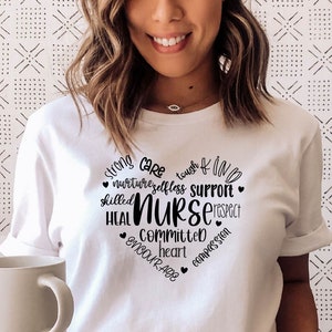 May include: White t-shirt with a black heart graphic that says "strong care tough & kind nurture selfless support skilled NURSE heal committed heart encourage compassion".