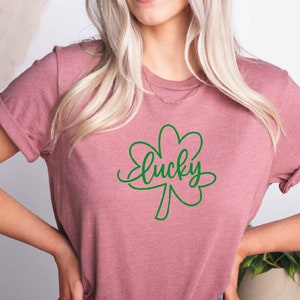 May include: A heather mauve t-shirt with a green four-leaf clover and the word "lucky" written in cursive.
