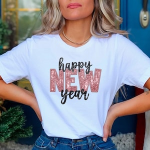 May include: A white t-shirt with a rose gold glitter design that says "happy new year".