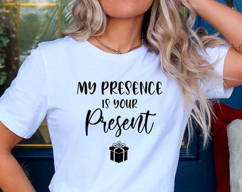 May include: White t-shirt with black text that reads "My presence is your present" with a small black gift box icon below the text.