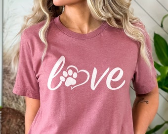 May include: A mauve t-shirt with a white graphic that says "love" with a paw print inside a heart.