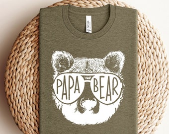May include: A green t-shirt with a white bear wearing sunglasses and the text "Papa Bear".