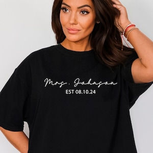 May include: Black oversized t-shirt with white text that reads "Mrs. Johnson EST 08.10.24"