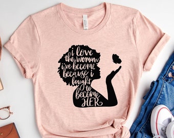 Peut inclure: Un t-shirt rose avec une silhouette noire d'une femme avec le texte "J'aime la femme que je suis devenue parce que j'ai lutté pour devenir ELLE".