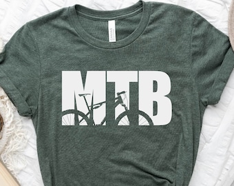 Peut inclure: Un t-shirt vert foncé avec le mot "MTB" en lettres blanches. Les lettres sont formées par la silhouette d'un vélo de montagne.