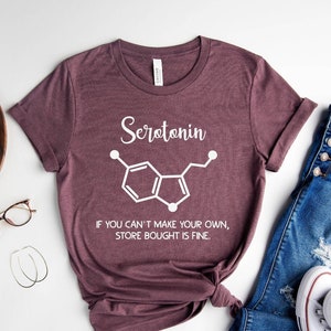 May include: A maroon t-shirt with a white graphic of the chemical structure of serotonin and the text "Serotonin. If you can't make your own, store bought is fine."