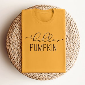 May include: A mustard yellow t-shirt with the text "hello pumpkin" in black lettering.
