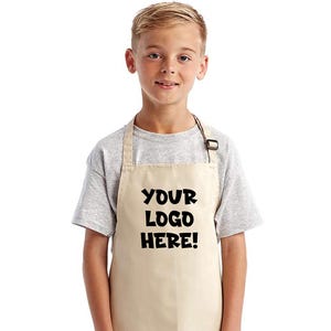 May include: A beige apron with the text "YOUR LOGO HERE!" in black, worn by a person. The apron has a neck strap and a simple design. The person is wearing a gray t-shirt and blue jeans.