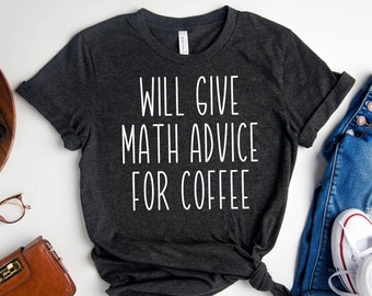 May include: Dark gray t-shirt with the text "WILL GIVE MATH ADVICE FOR COFFEE" in white. The shirt is styled with blue jeans and white sneakers. A brown wallet, glasses, and a succulent plant are also in the image.