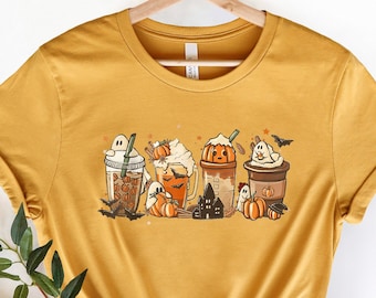 May include: A mustard yellow t-shirt with a graphic of five fall-themed coffee drinks with pumpkins, ghosts, and bats.