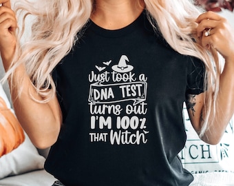 May include: A black t-shirt with a white graphic that says "Just took a DNA test turns out I'm 100% THAT Witch" with a witch's hat and bats above the text.