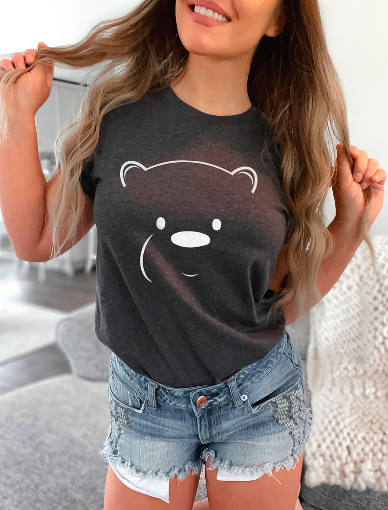 May include: A dark gray t-shirt with a white outline of a bear face. The bear has a small nose and two eyes.