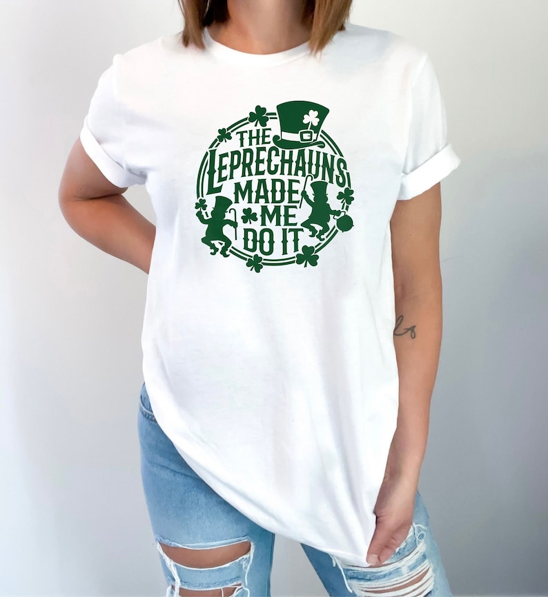 May include: White t-shirt with a green graphic design featuring two leprechauns and the text "The Leprechauns Made Me Do It".