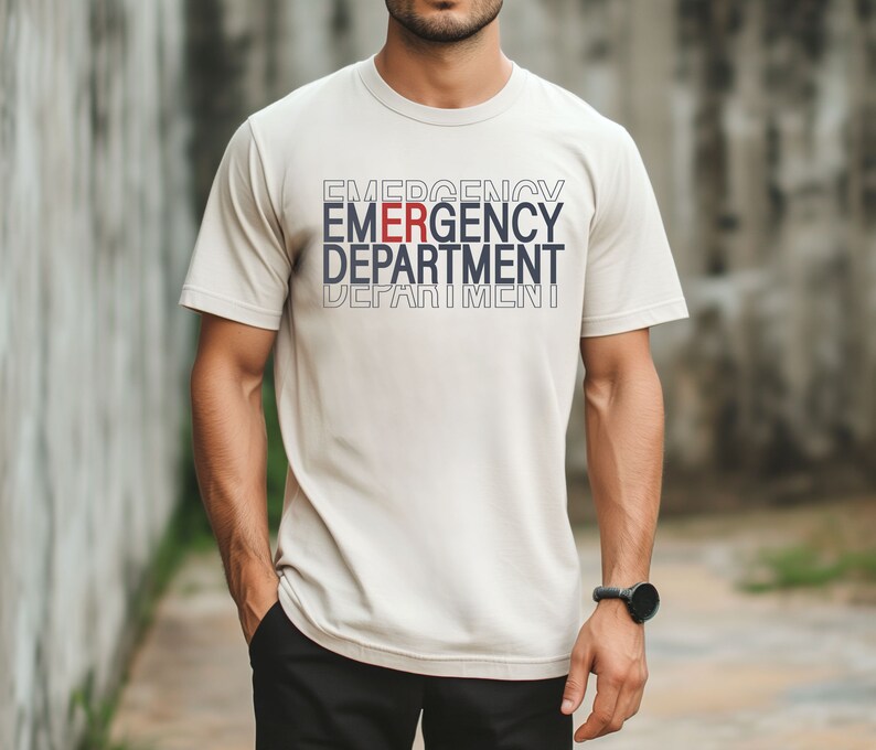 Może przedstawiać: Beżowa koszulka z nadrukiem "EMERGENCY DEPARTMENT" z przodu w kolorze białym i niebieskim, z wyr&oacute;żnioną czerwoną literą "E" w słowie "EMERGENCY".