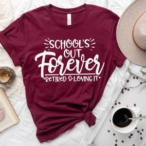 Puede incluir: Camiseta de color granate con texto blanco que dice "School's Out Forever *Retired & Loving It*"