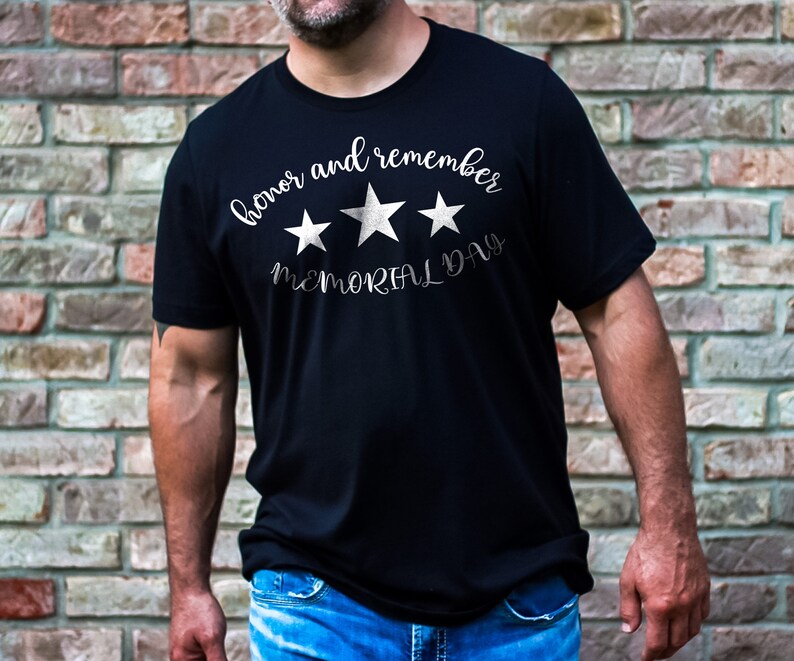 以下が含まれることがあります： 白い文字で「honor and remember MEMORIAL DAY」と書いてある、3つの白い星がついた黒いTシャツ