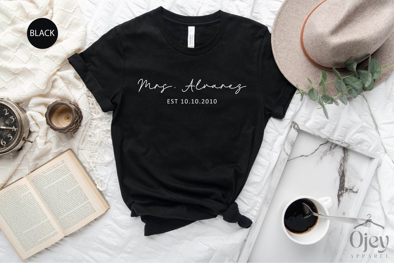 May include: Black t-shirt with white text that reads "Mrs. Alvarez EST 10.10.2010".