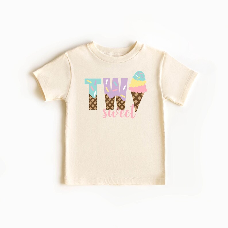 May include: A light beige t-shirt with the words "TWO sweet" printed on it. The "TWO" is made up of ice cream cones with sprinkles and the word "sweet" is in pink.