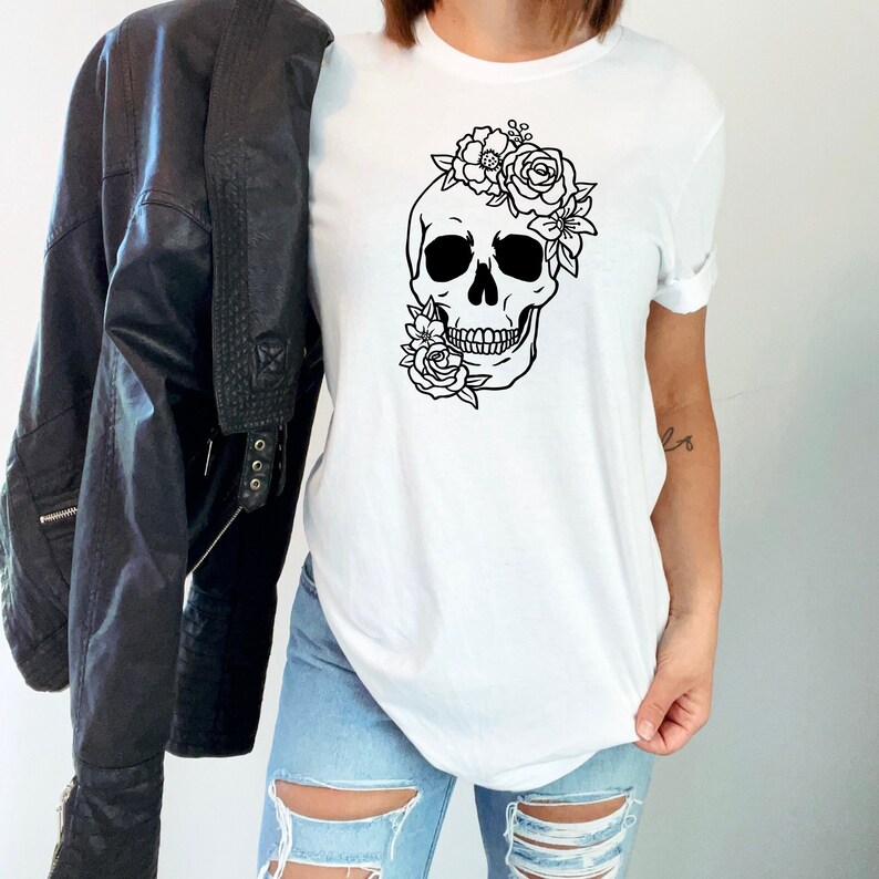 Peut inclure: T-shirt blanc avec un motif noir et blanc d'un cr&acirc;ne surmont&eacute; de fleurs.