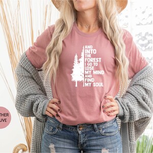 May include: A heather mauve t-shirt with a white graphic of a tree and the text "And into the forest I go to lose my mind and find my soul".