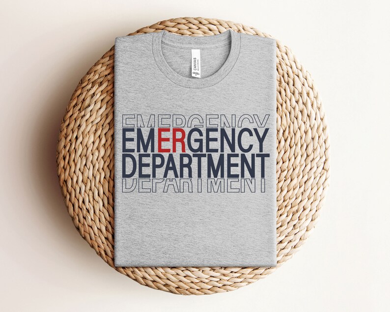 Może przedstawiać: Szary t-shirt z nadrukiem "EMERGENCY DEPARTMENT" w kolorze granatowym i czerwonym.