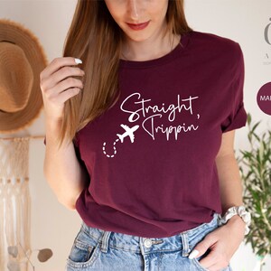 May include: A maroon t-shirt with the text "Straight Trippin'" in white lettering and a small airplane graphic.