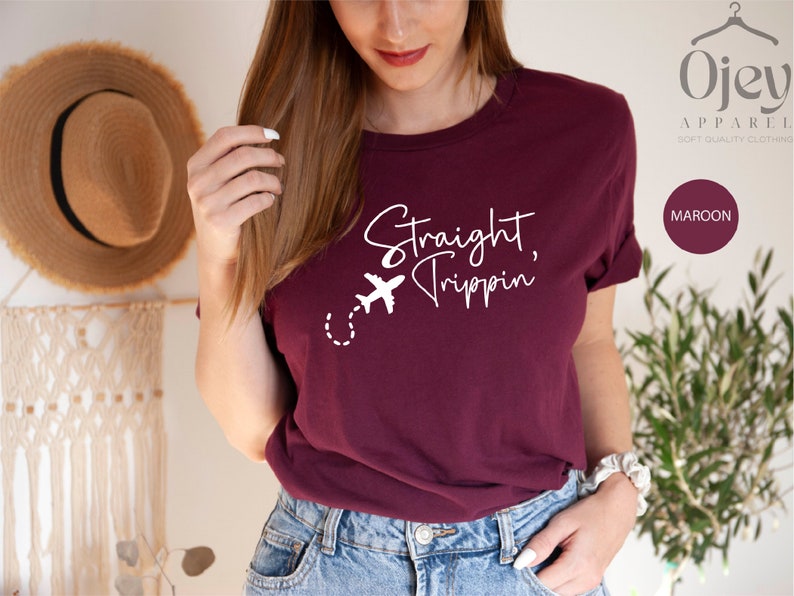 May include: A maroon t-shirt with the text "Straight Trippin'" in white lettering and a small airplane graphic.