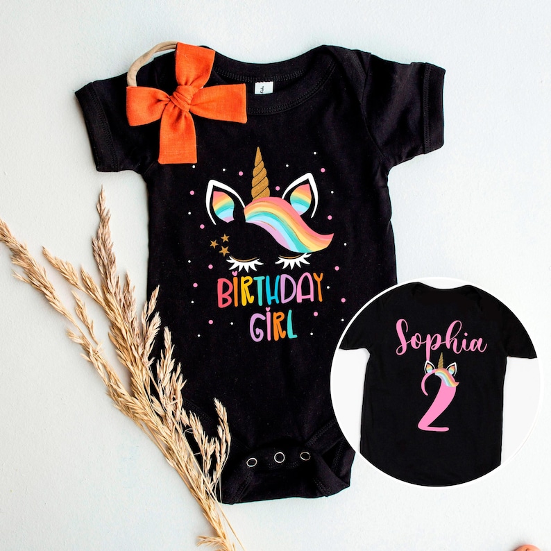 May include: Black bodysuit with a rainbow unicorn graphic and the text "Birthday Girl". A matching black t-shirt with the name "Sophia" and a pink unicorn with the number "2".