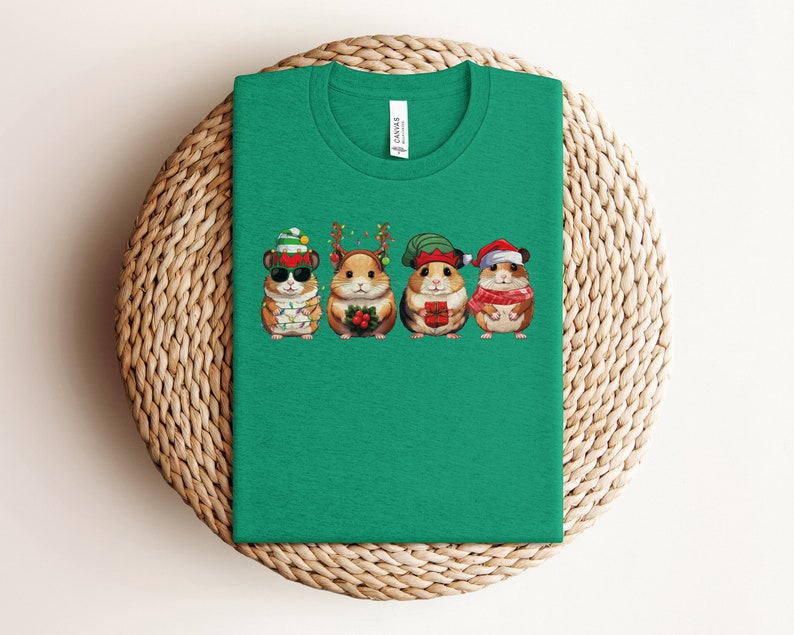May include: Green t-shirt with a graphic of four hamsters wearing Christmas hats and holding gifts. The hamsters are wearing Santa hats, elf hats, and reindeer antlers.