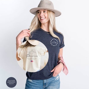Peut inclure: Un t-shirt bleu marine chin&eacute; avec un motif blanc au dos qui dit "The United States of America - The Land of the Free - Home of the Brave" avec un petit drapeau am&eacute;ricain. Le devant du t-shirt a un motif blanc avec des &eacute;toiles et le texte "Since 1776".
