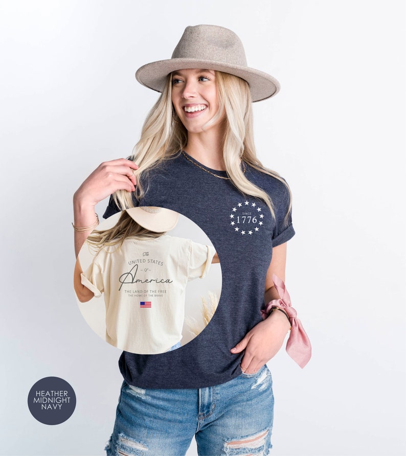 Peut inclure: Un t-shirt bleu marine chin&eacute; avec un motif blanc au dos qui dit "The United States of America - The Land of the Free - Home of the Brave" avec un petit drapeau am&eacute;ricain. Le devant du t-shirt a un motif blanc avec des &eacute;toiles et le texte "Since 1776".