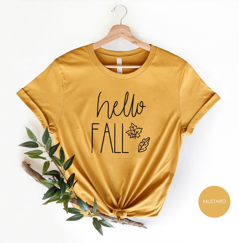 May include: A mustard yellow t-shirt with the text "hello fall" and a small leaf design.