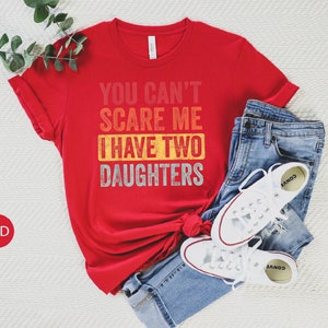 Puede incluir: Camiseta roja con un gr&aacute;fico vintage desgastado que dice "You Can't Scare Me I Have Two Daughters".