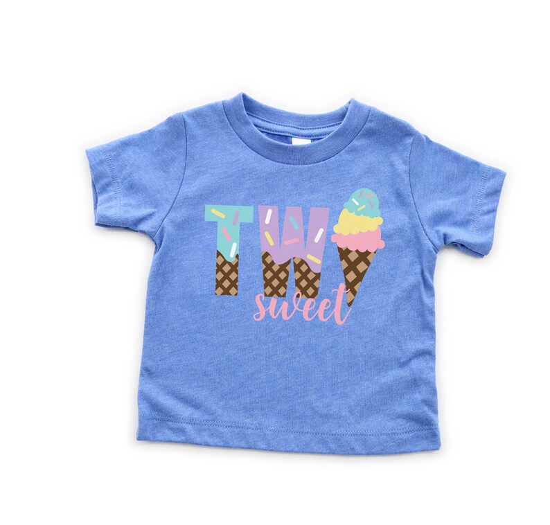 May include: Blue short-sleeved t-shirt with the text "TWO sweet" in pink and white. The number two is made of ice cream cones with sprinkles.