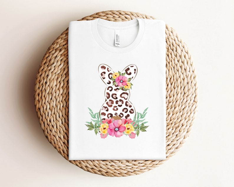 May include: White t-shirt with a brown and black leopard print Easter bunny with pink and yellow flowers.