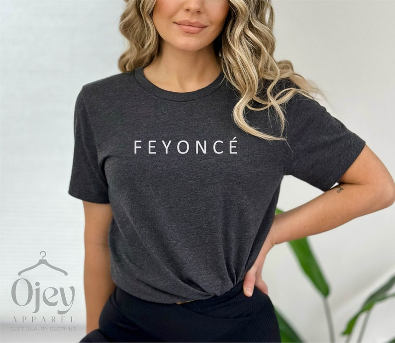 Pu&ograve; includere: Una maglietta grigia scura con il testo "FEYONC&Eacute;" stampato in bianco sul davanti.
