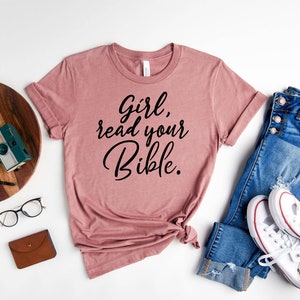 Pode incluir: Uma camiseta cor malva com o texto "Girl, read your Bible." impresso em preto.