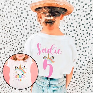 May include: White t-shirt with a pink unicorn and the number 5 on the back. The front of the shirt has a unicorn with a rainbow mane and the text "Birthday Girl".