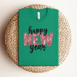May include: Green t-shirt with the text "happy new year" in pink glitter letters with black outlines.