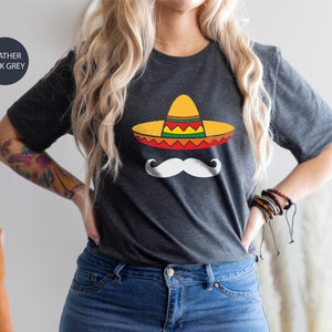 May include: A heather dark grey t-shirt with a graphic of a white mustache and a yellow, red, and green sombrero.