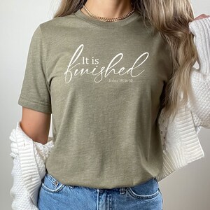 May include: A green t-shirt with the text "It is finished" in white cursive lettering and the scripture reference "John 19:28-30" underneath.
