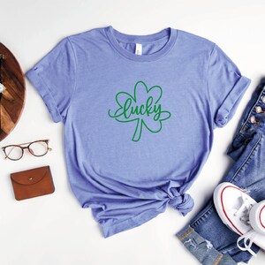 May include: A heather columbia blue t-shirt with a green shamrock and the word "lucky" written in cursive.